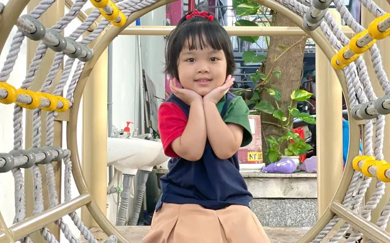Bé gái ngồi trong vòng leo của sân chơi