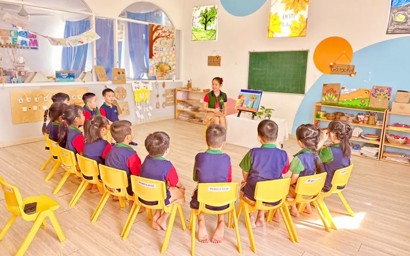 Các bé ngồi ghế thành vòng nghe cô kể chuyện trong lớp