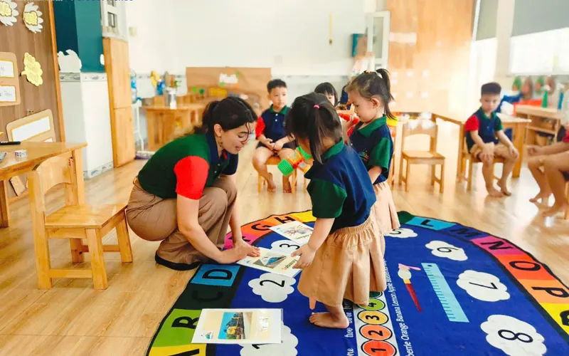 Cô ngồi trên thảm tròn cùng các bé xem tranh